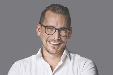 Porträt blonder, lachender Mann mit Brille in weißem Hemd. 