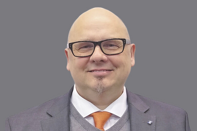 Porträt lächelnder Mann mit Brille. Anzug und Krawatte.