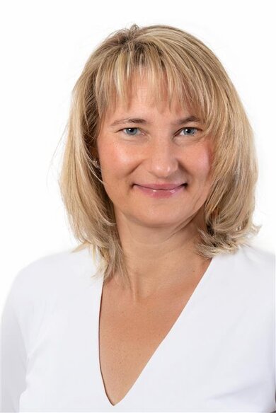 Porträt blonde, lächelnde Frau. Weißes Oberteil.