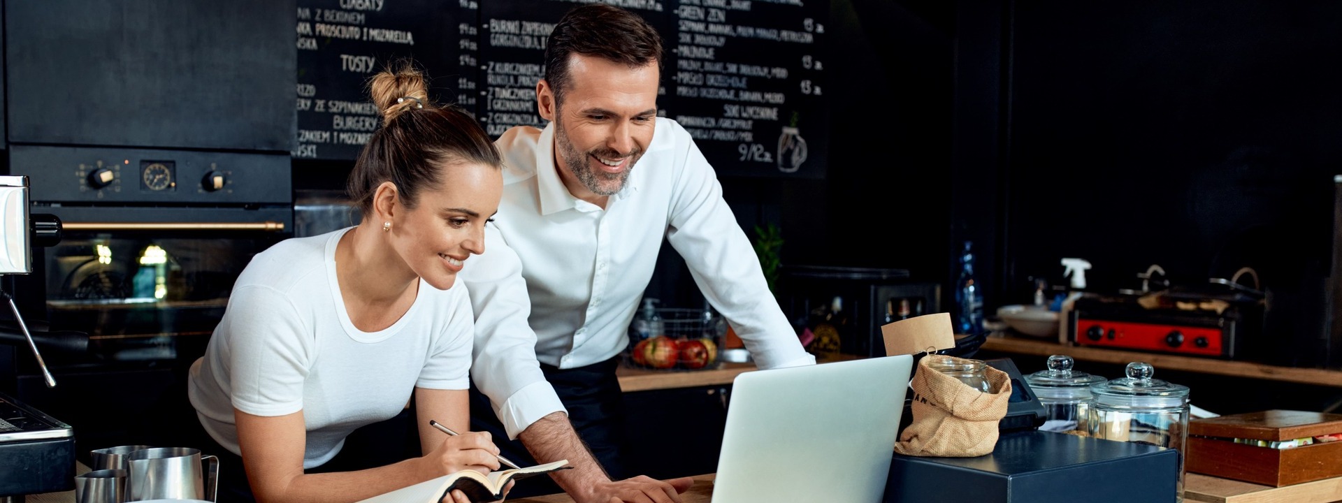 Mann und Frau am Tresen eines Cafes vor einem Laptop