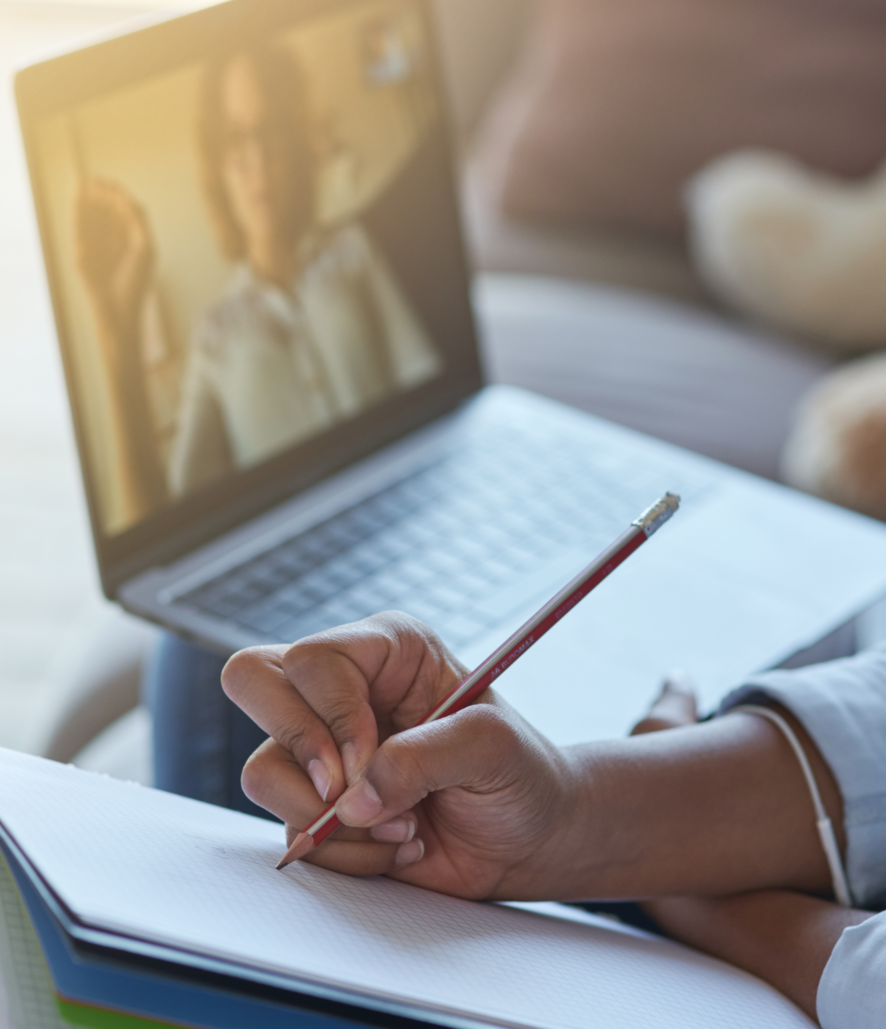 Aufgeklappter Laptop mit Bild von Frau, Hand schreibt im Vordergrund mit 