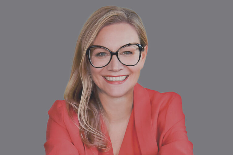 Lachende, blonde frau mit großer Brille. Rotes Oberteil