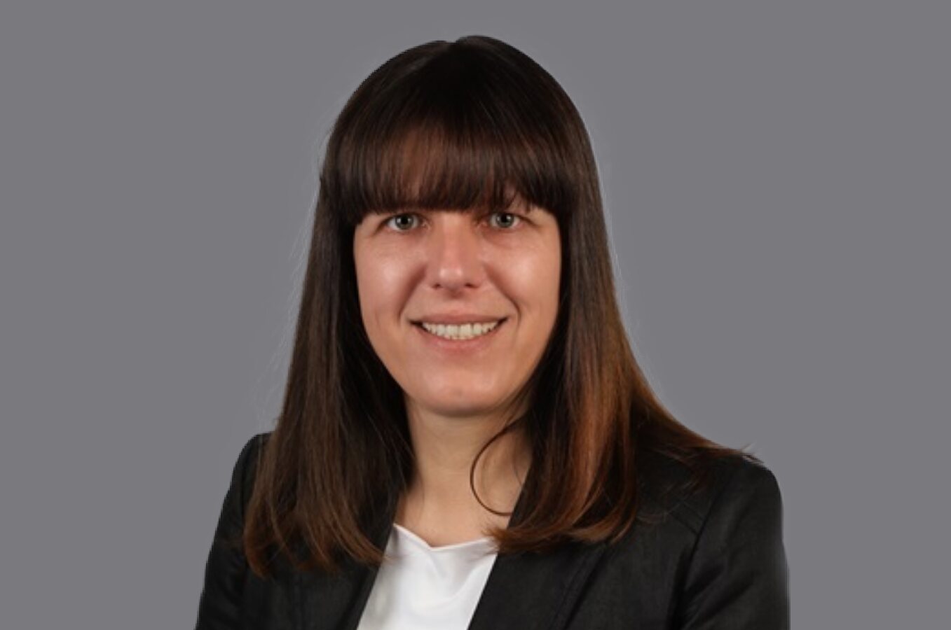    Braunhaarige Frau mit Pony lächelt in die Kamera