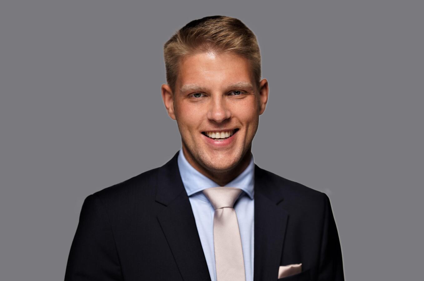 Blonder Mann in Anzug lächelt in die Kamera