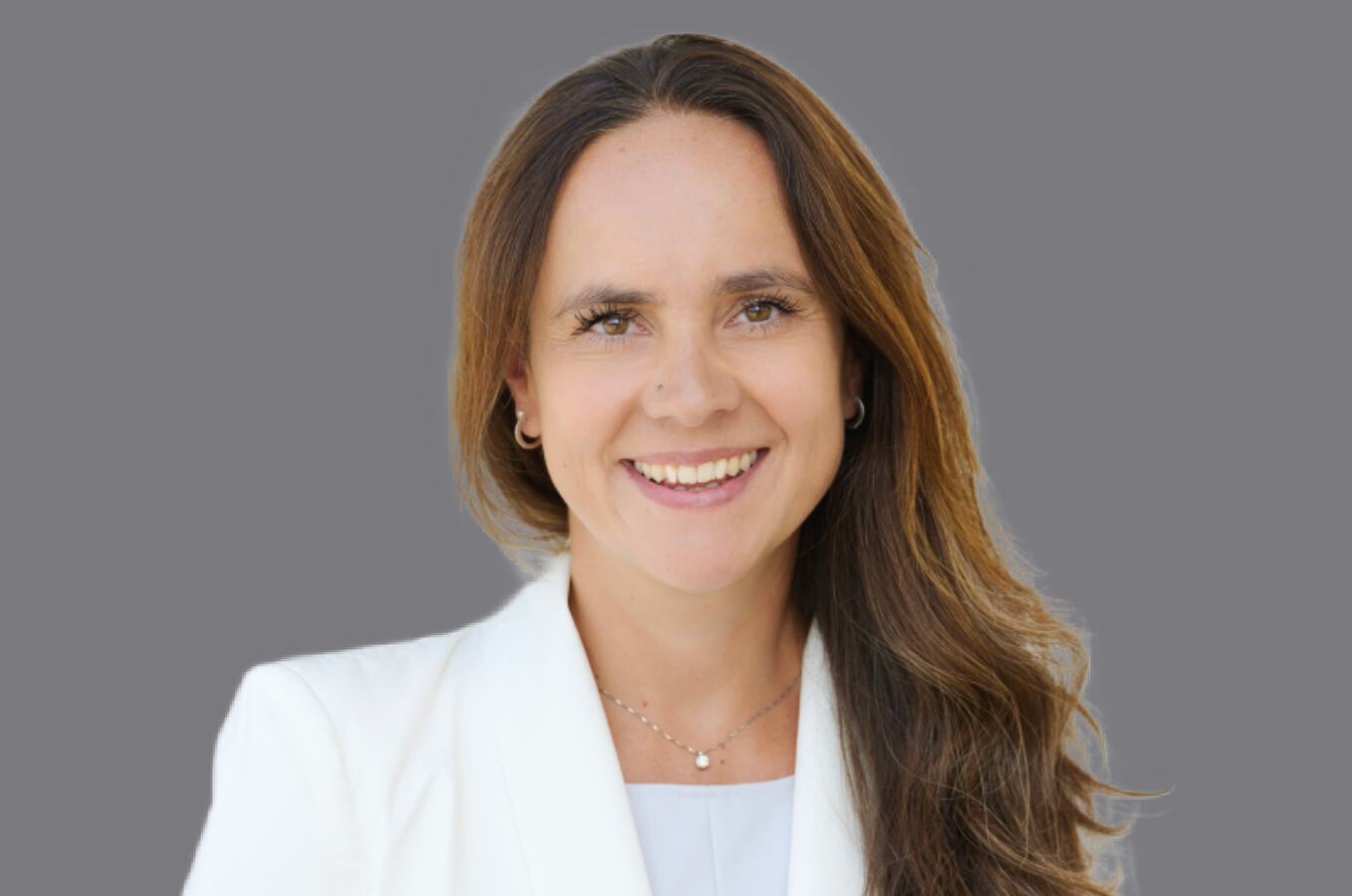 Lächelnde braunhaarige Frau mit offenen Haaren in weißem Blazer