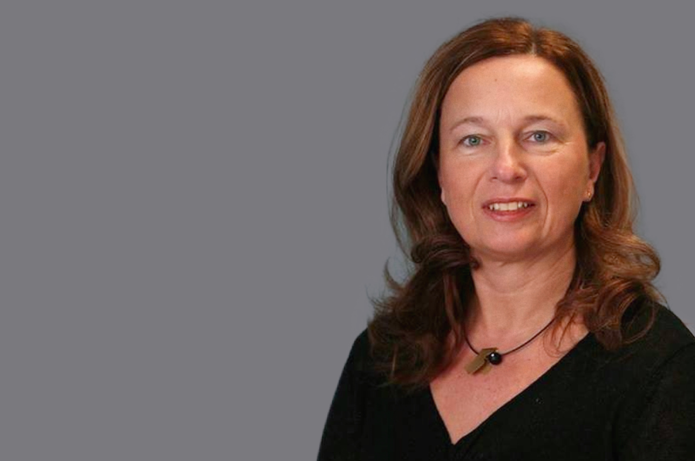 Lächelnde braunhaarige Frau mit offenen Haaren. Schwarzes Oberteil